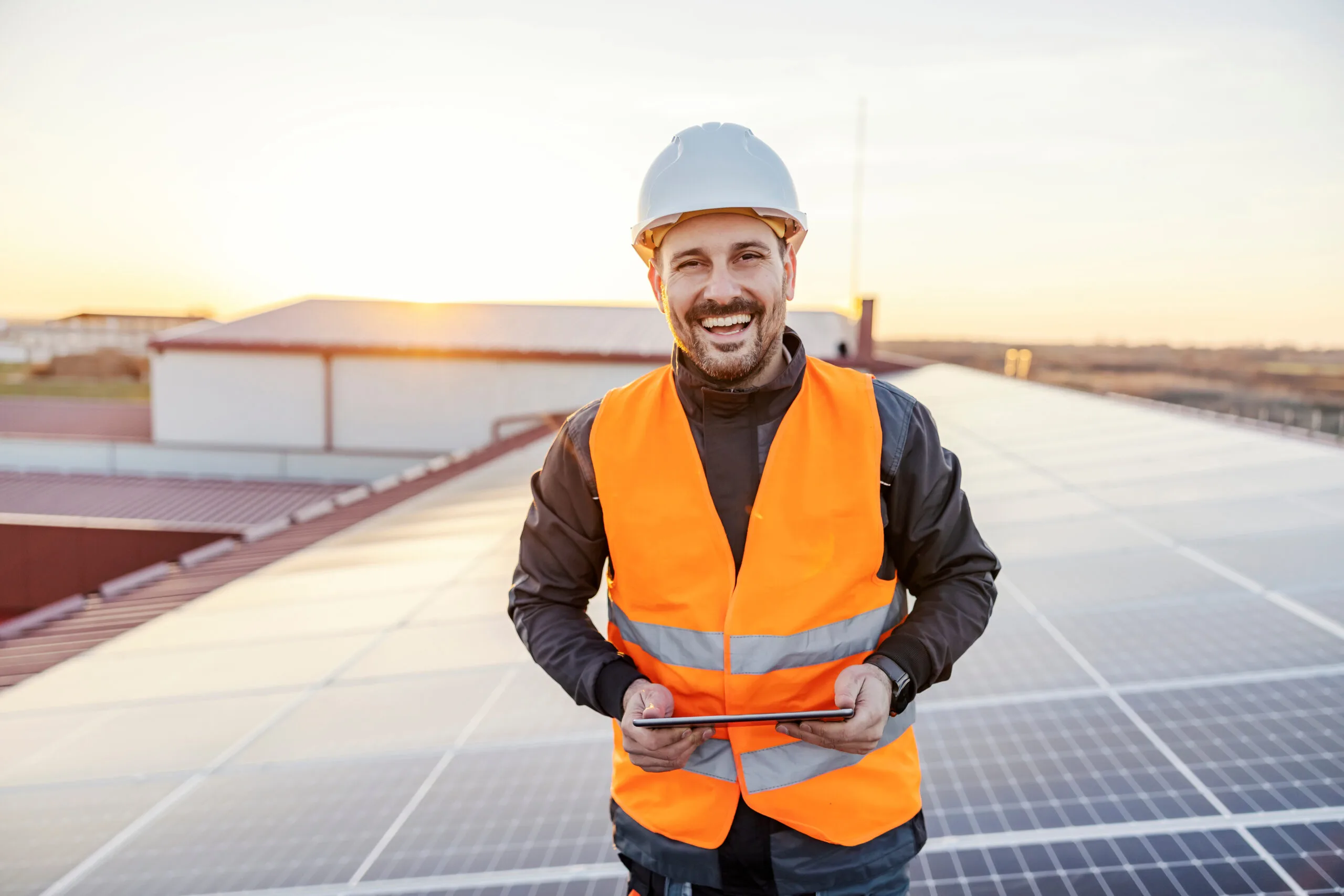 Solar site survey technician using tablet on residential rooftop during solar panel installation